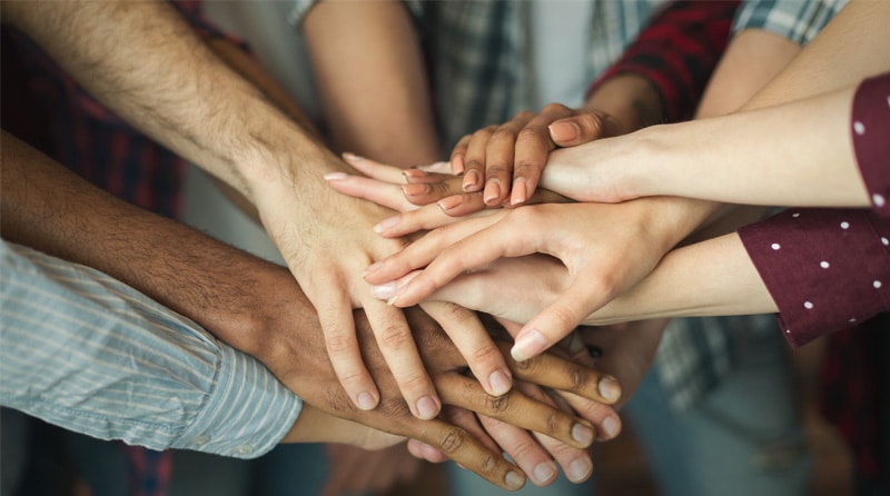 Diverse people all holding hands over hands